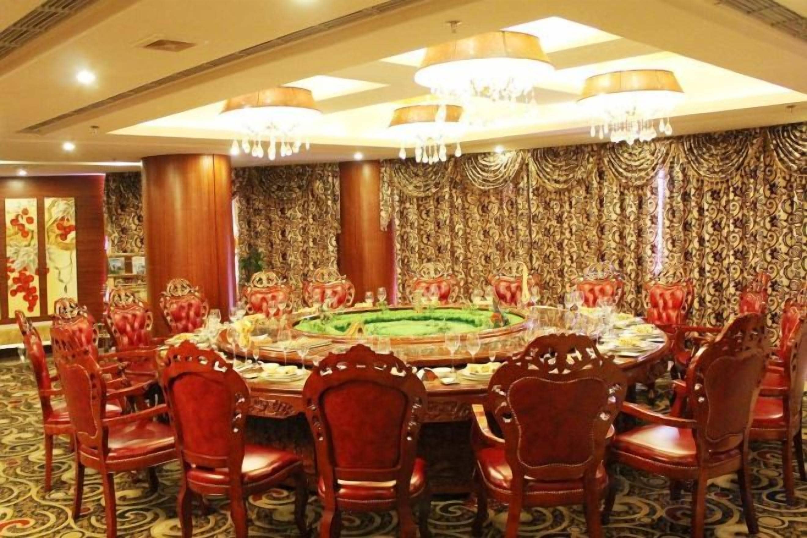 Un comedor formal con una mesa redonda, sillas tapizadas en rojo y adornos ornamentales en las paredes.