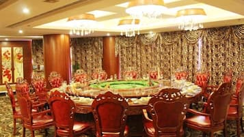 Un comedor formal con una mesa redonda, sillas tapizadas en rojo y adornos ornamentales en las paredes.