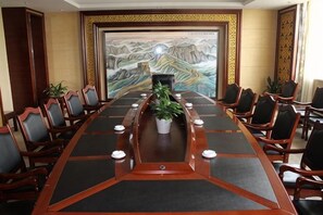 Un salón de conferencias con una larga mesa, sillas y un cuadro en la pared.