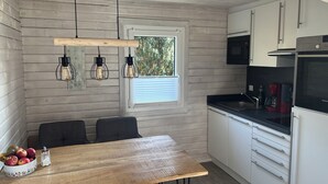 Eine kompakte Küche mit Holztisch, drei Stühlen, einem Fenster und modernen Geräten.