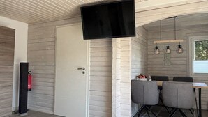 Eine moderne Küche mit Essbereich, weißen Ziegelwänden und einem flachbildfernseher über der Tür.