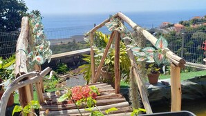 Un puente de madera con vistas al océano y un jardín con plantas en macetas.