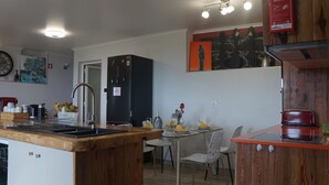 Una cocina compacta con encimera de madera, pileta integrada y zona de comedor con mesa y sillas.
