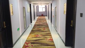 A long, narrow hallway with a patterned carpet, doors on both sides, and a window at the end. - Erenhot Jingtai Hotel (Erenhot)