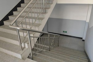 Una escalera con barandillas de metal y piso alfombrado.