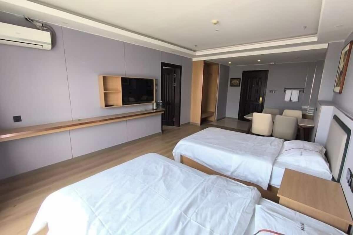 A hotel room with two beds, a TV, a desk, and a wardrobe.