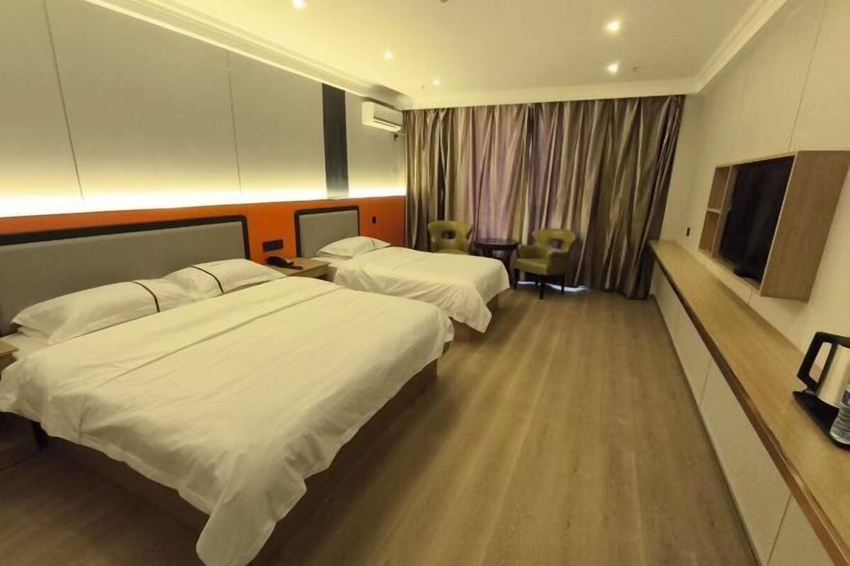 A hotel room with two beds, a TV, a desk, and a chair.