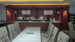A conference room with a long table and cushioned chairs, a wooden panel wall, and a service counter with food containers. - Erenhot Jingtai Hotel (Erenhot)