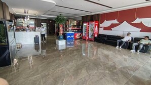 A hotel lobby with a reception desk, seating area, vending machines, and a decorative wall. - Erenhot Jingtai Hotel (Erenhot)