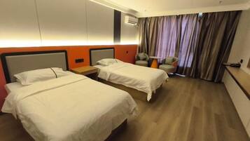 Una habitación de hotel con dos camas, una mesita de noche, una silla y un ventanal con cortinas.