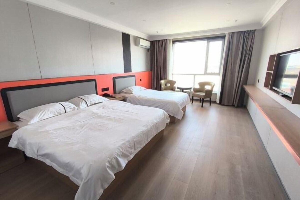 Una habitación de hotel con dos camas, televisión, escritorio y una silla.