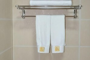 A bathroom with a towel rack holding two white towels and a folded towel above it. - Erenhot Jingtai Hotel (Erenhot)