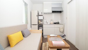 Ein kleines Hotelzimmer mit Bett, einer Küchenzeile und einem Essbereich.