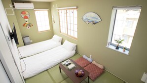 Ein Zimmer mit zwei Betten, einem kleinen Tisch mit einer Dekoration, einem Fenster mit Blick und einer Wand-Klimaanlage.