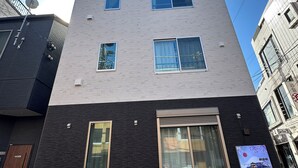 Ein mehrstöckiges Gebäude mit moderner Architektur, das verschiedene Fensterformen und einen markanten Eingang mit großen Glasüren aufweist.