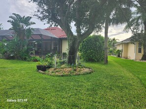Stroll through the lush garden, surrounded by tropical plants and a majestic tree, to the charming single-family home with an outdoor space.