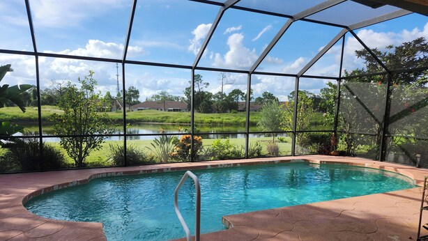 An indoor swimming pool with a view of a lake and greenery. - Charming 3-bedroom house with pool and WiFi in North Port in amazing community (North Port)