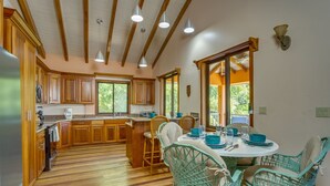 Una cocina con armarios de madera, una isla central y sillas de mimbre color turquesa.