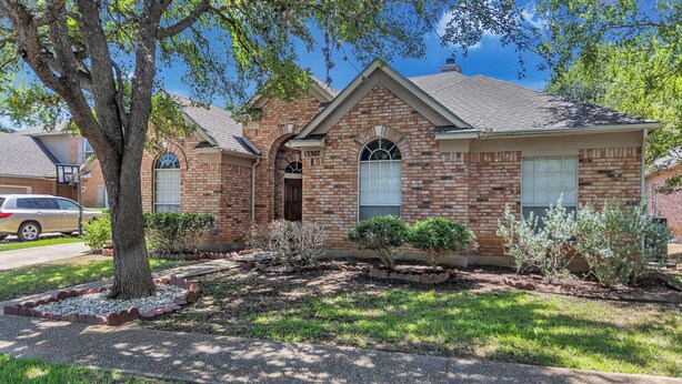 A single-story brick house with a front entrance, a garage door, and a small front yard with landscaping. - Relax in This Spacious 4BR San Antonio Home with WiFi and AC (San Antonio)