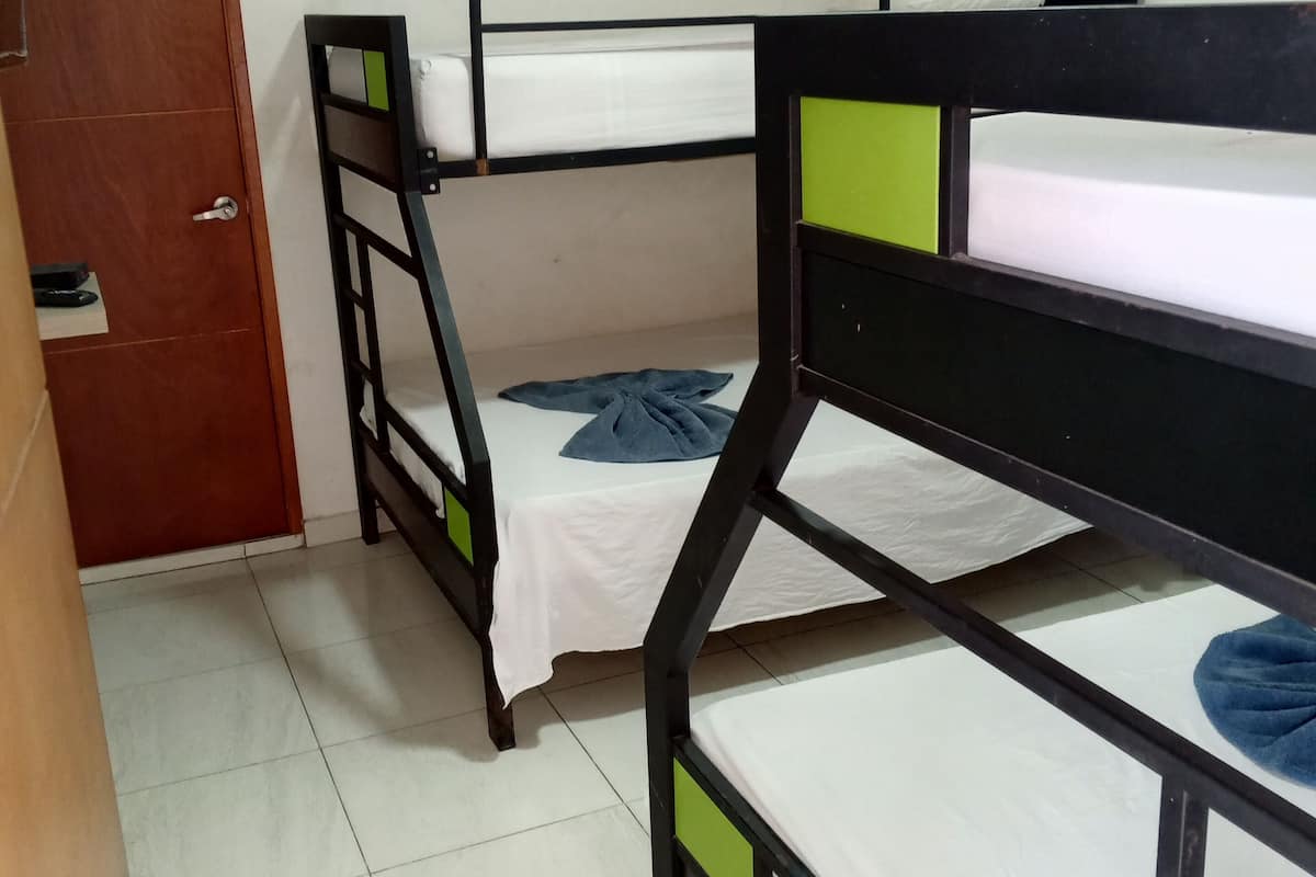 A room with bunk beds, a wooden door, and a tiled floor.