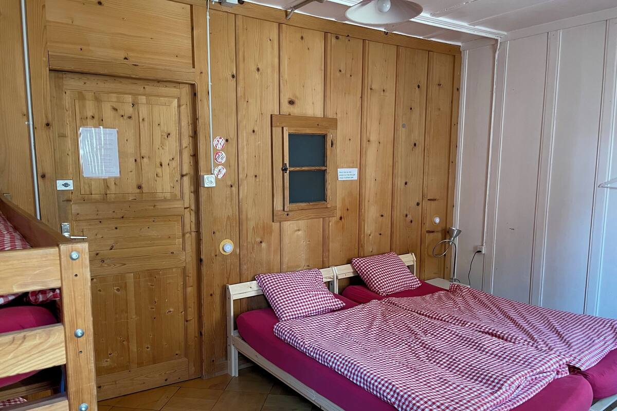 A wooden-paneled room with a bed, a window, and a door.