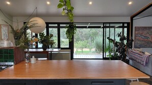 A modern kitchen with a wooden countertop, black cabinets, and a large window offering a view of the outdoors.