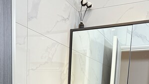 Een moderne badkamer met een marmeren wastafel, een zwarte kraan en een grote spiegel.