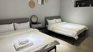Een hotelkamer met twee bedden, een nachtkastje met een lamp, een wandairconditioner en decoratieve wanddecoraties.