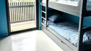 Une chambre avec un lit superposé, une grande fenêtre et une vue sur une terrasse en bois.