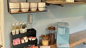 Una estación de café con varias estanterías que contienen tazas, tarros y una cafetera.