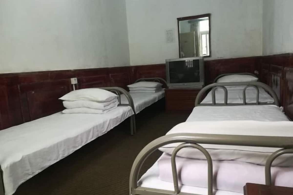 Quarto com duas camas de solteiro, televisão e espelho na parede.