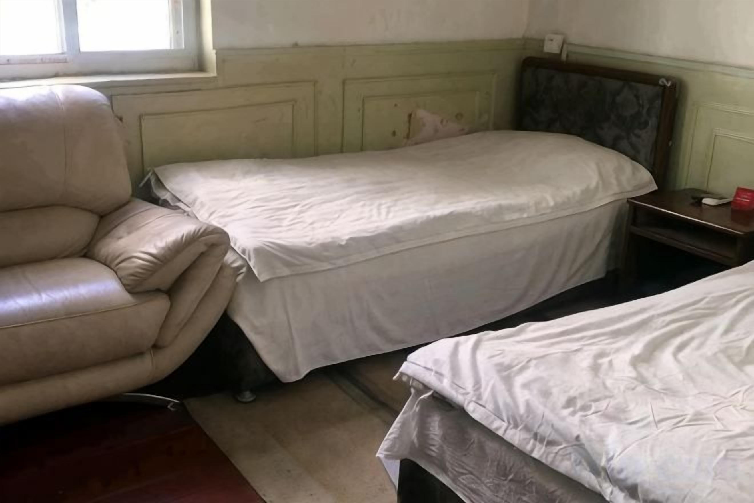 A room with two beds, a chair, and a small table.