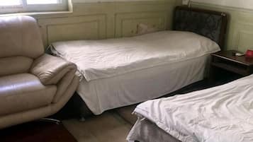 A room with two beds, a chair, and a small table.