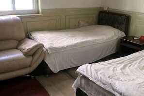 Une chambre avec deux lits, une chaise et une petite table.