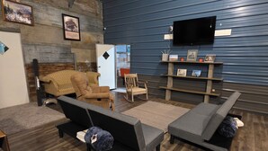 A room with a sofa, a chair, a small table, and a TV mounted on the wall. - Great place for allot of fun events & all your people under 1 roof low cost! (Hunnewell)