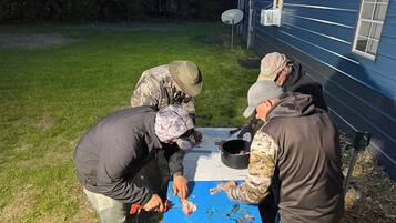A group of people preparing food outdoors near a house with a satellite dish.