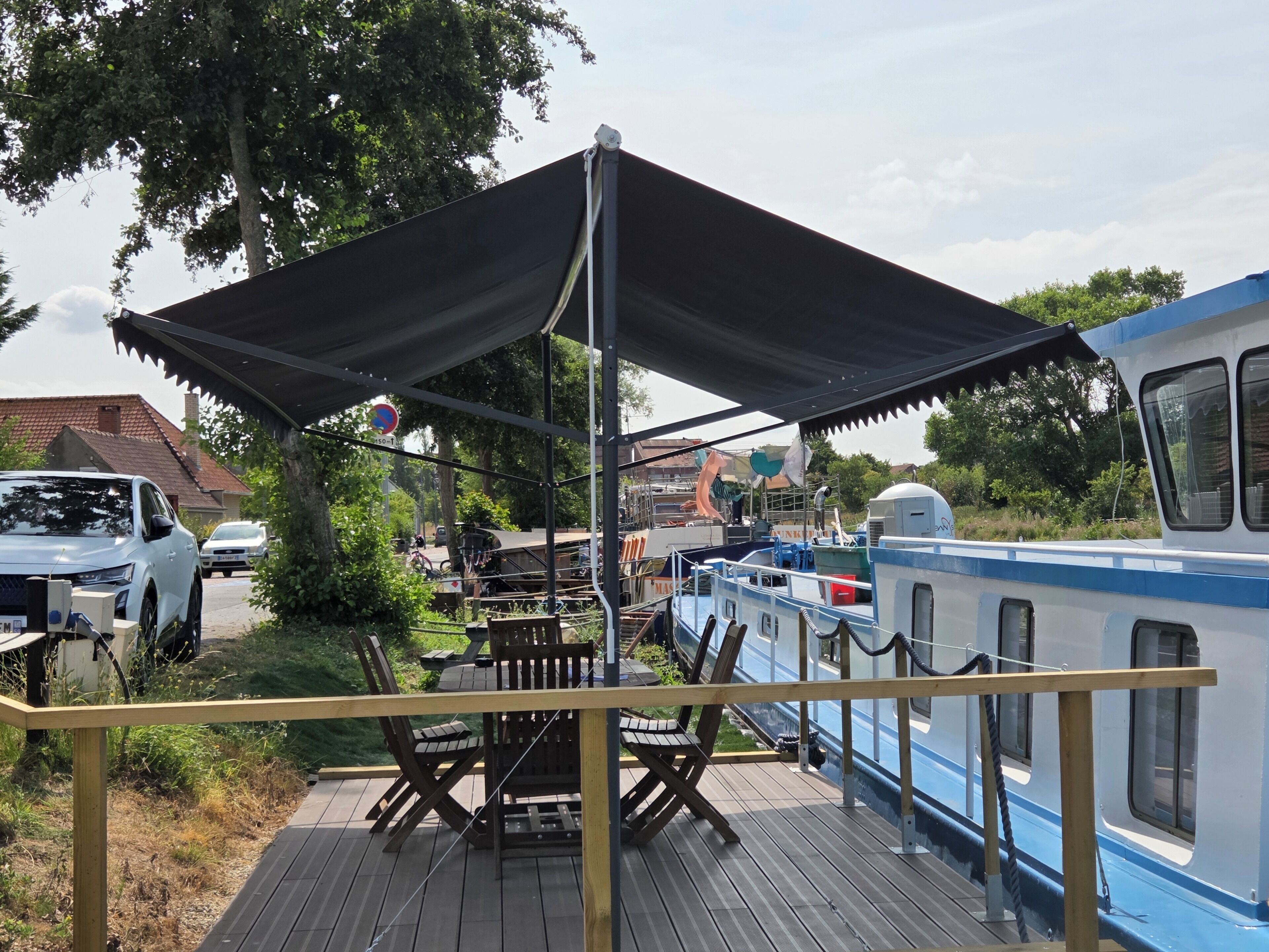 En terrasse med udendørs møbler, et overdækket område og en båd i nærheden.