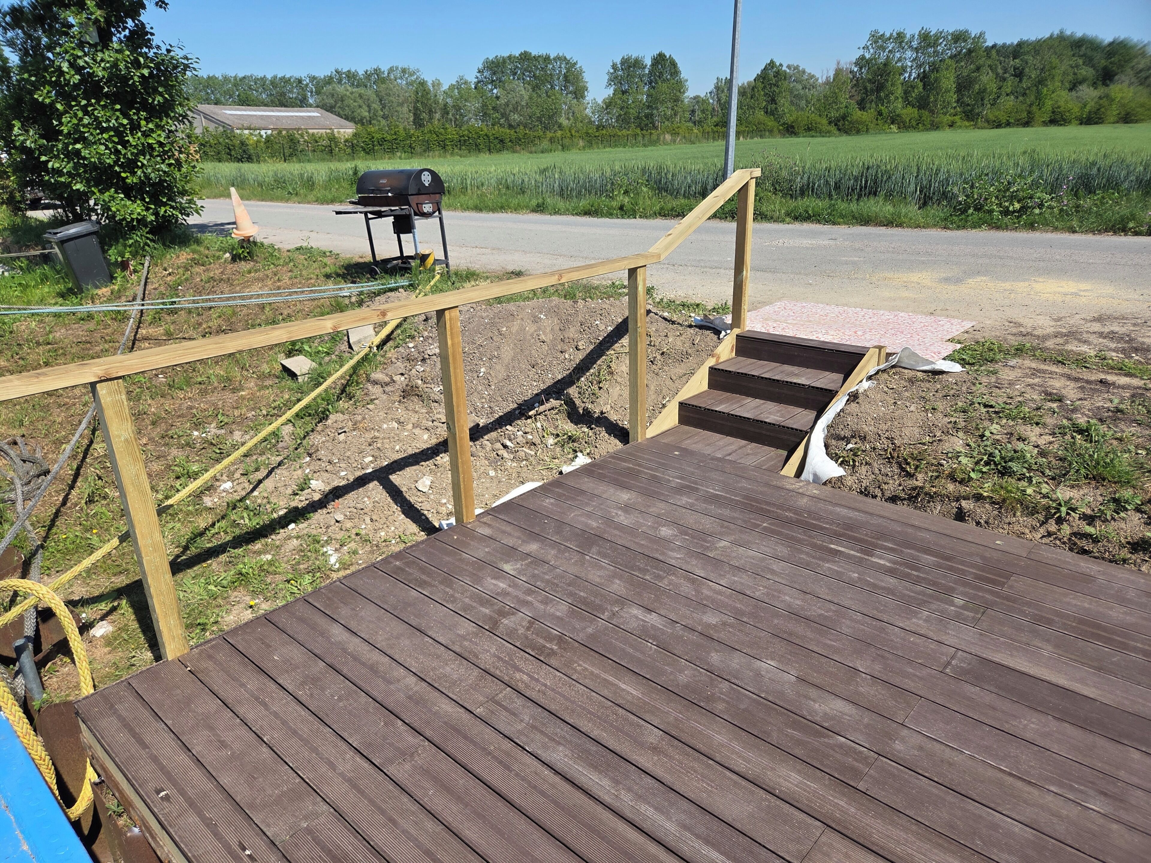 Een houten terras met een trap naar een gazon.