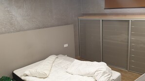 Een slaapkamer met een bed, een kledingkast en een houten plank.