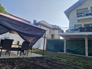 A covered patio area with outdoor furniture, a pool, and a building with a balcony. - Apartman Villa E&M (Bihac, Golubic)