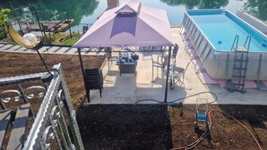 Un jardin avec une piscine, un patio couvert et une vue sur un lac.