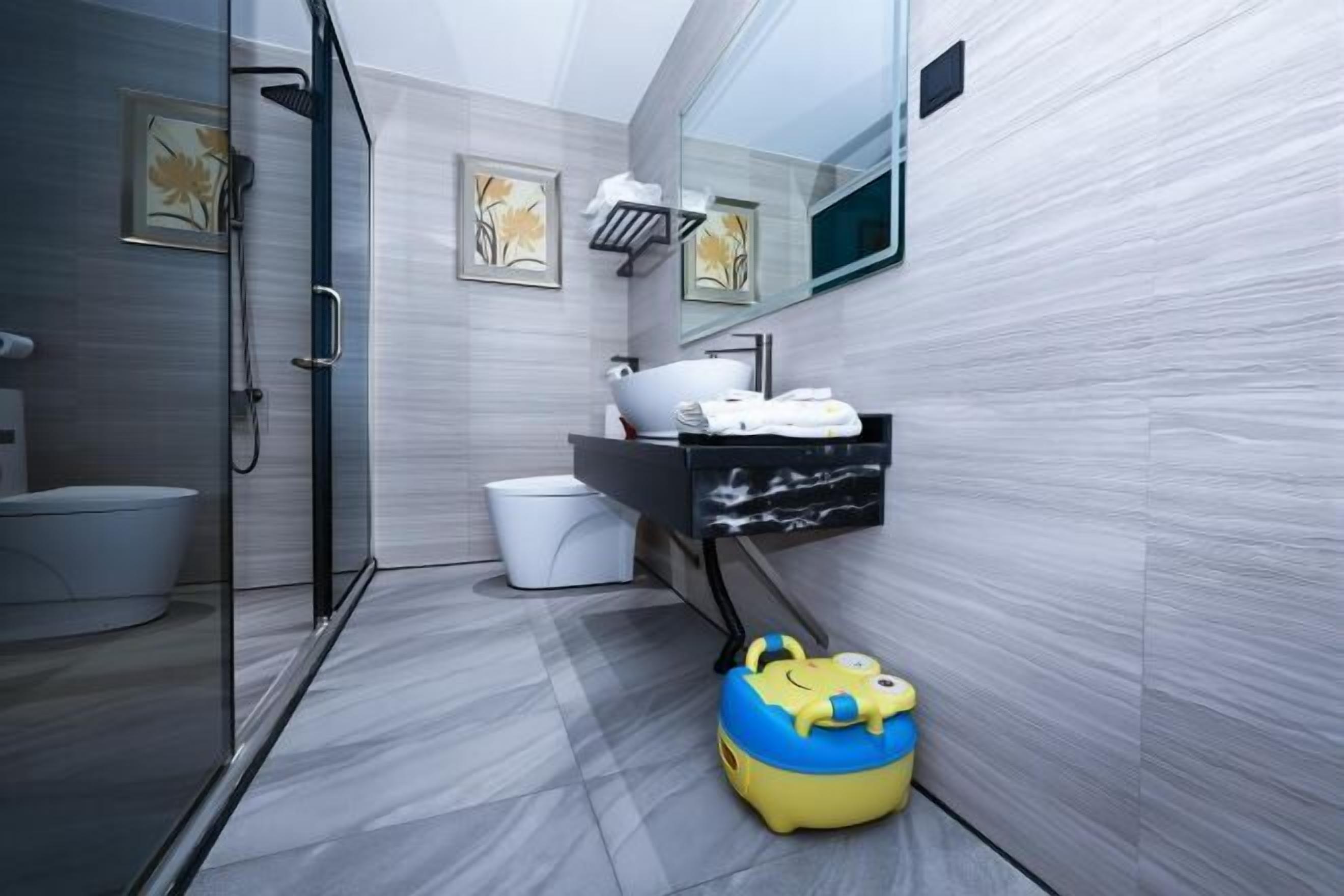 A modern bathroom with a glass shower enclosure, a toilet, a sink with a black countertop, and a mirror above the sink.