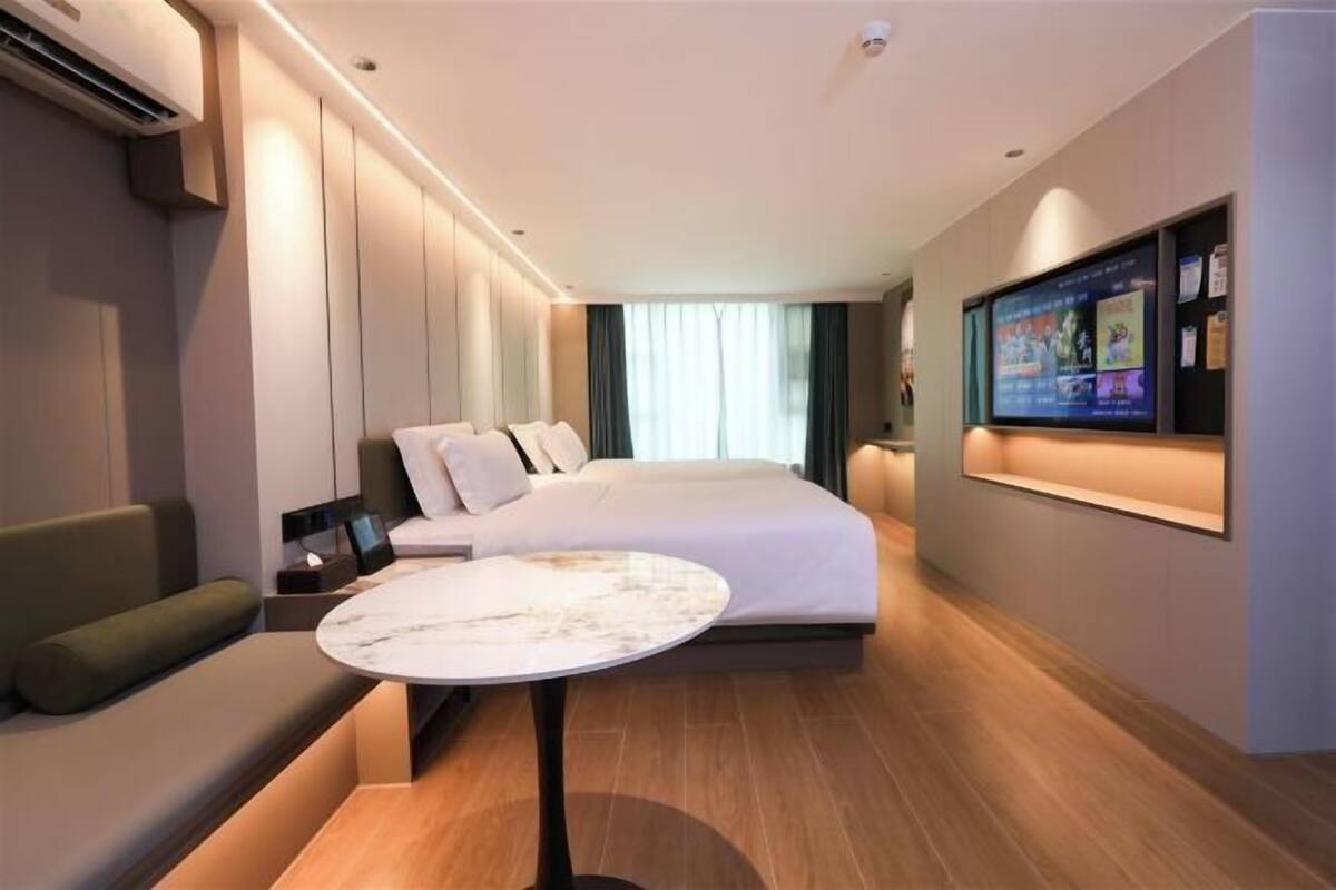 Una habitación de hotel moderna con una cama grande, una zona de estar, un televisor de pantalla plana y una mesita.