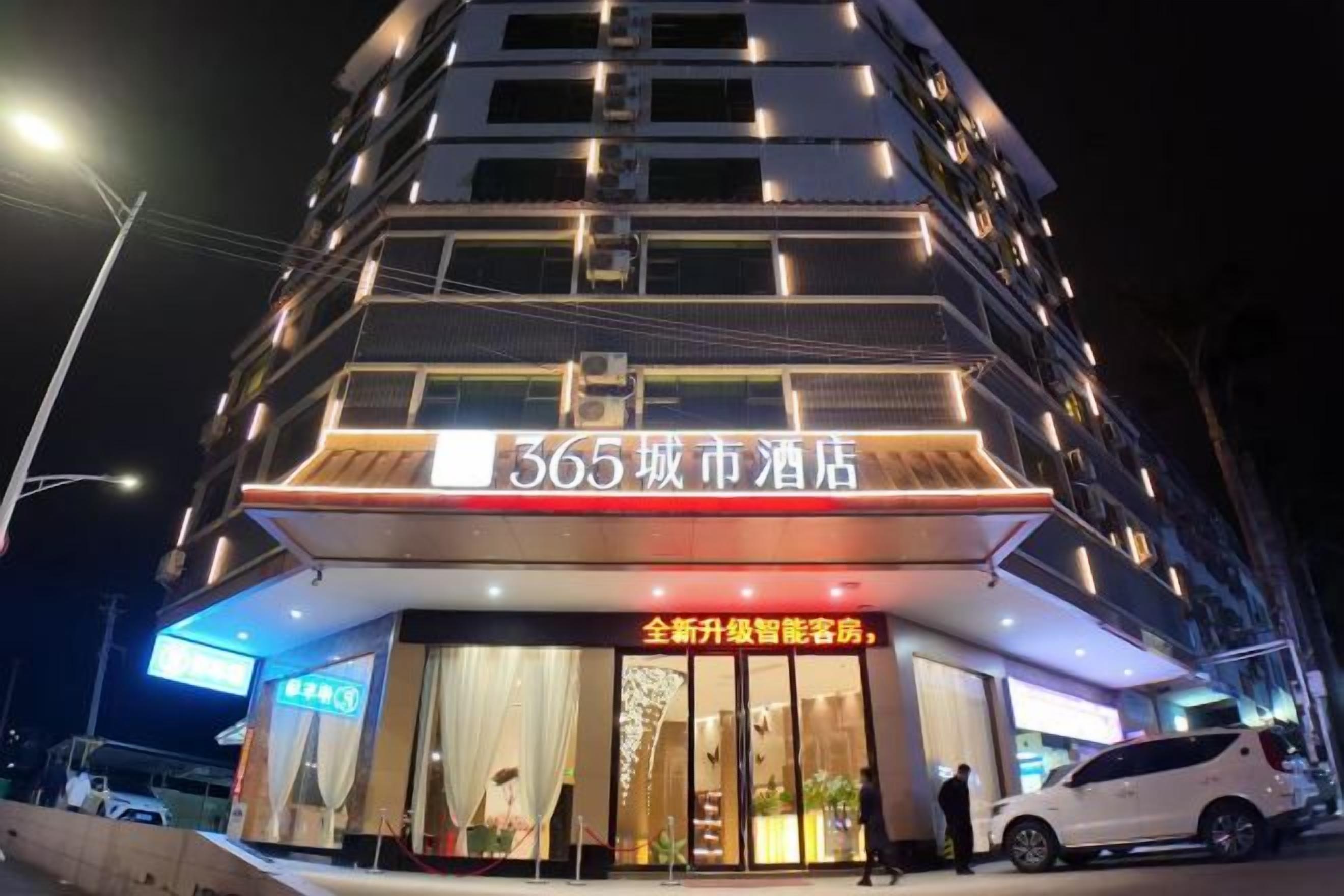 A multi-story hotel with illuminated signage, a visible entrance, and a car parked outside.