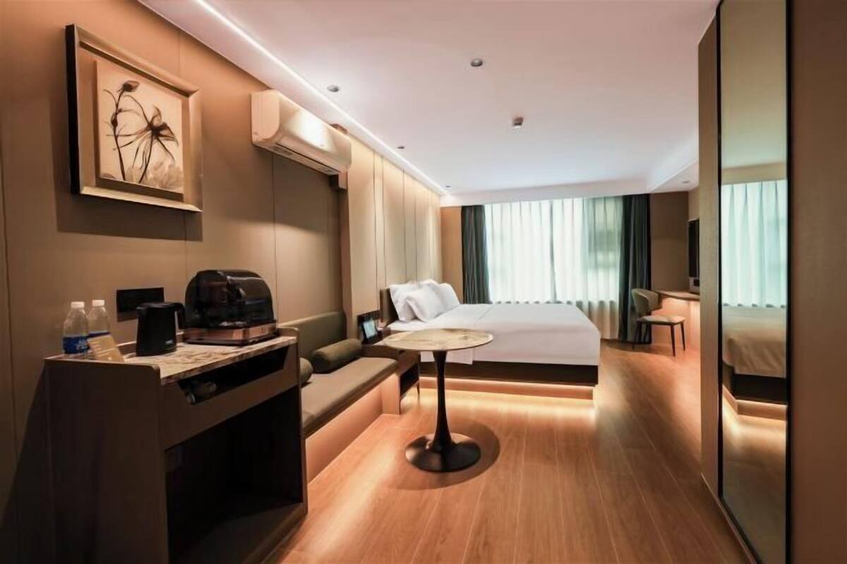 Una habitación de hotel moderna con una cama, un escritorio con cafetera, un sofá y una pequeña mesa.