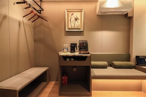 A modern bathroom with a bench, a sink area with a coffee maker, and a framed artwork on the wall. - 365 City Hotel (Meizhou)