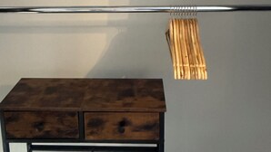 Une pièce comprenant une commode en bois et deux étagères en métal avec des cintres en bois.