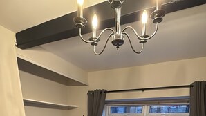 Un salon avec un canapé gris, un téléviseur à écran plat, une cheminée et une fenêtre donnant sur la rue.