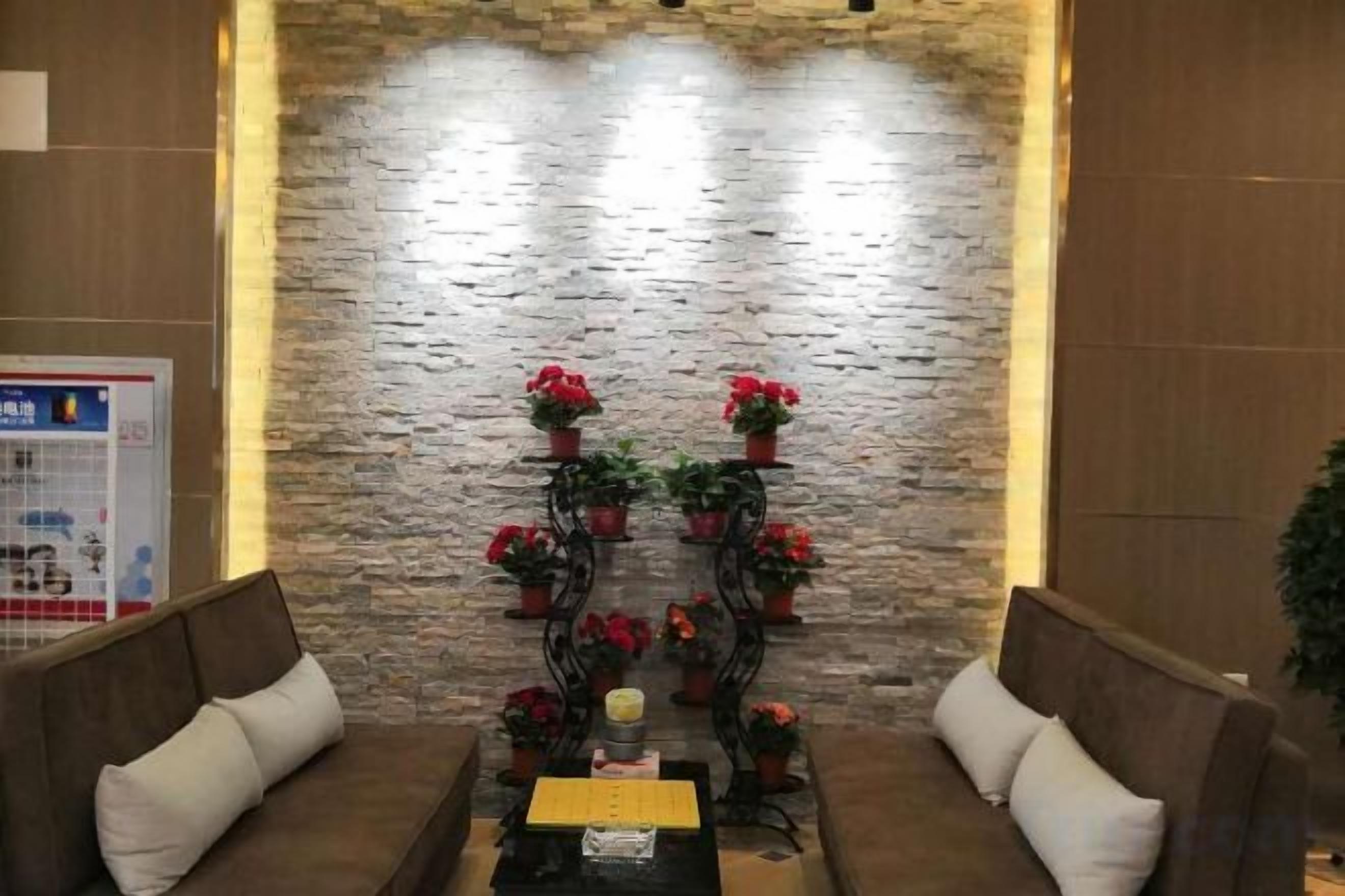 A reception area with a stone wall, a reception desk, and two sofas with cushions.