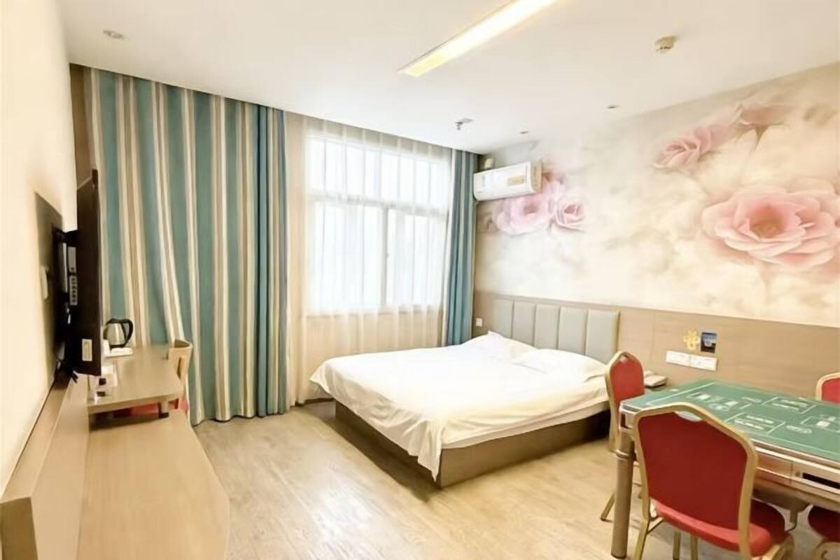 Une chambre d’hôtel équipée d’un lit, d’un bureau, d’une chaise, d’une table et d’un climatiseur fixé au mur.